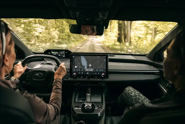 Subaru e-Outbacks förarplats med ratt, mittskärm och utsikt mot skogen