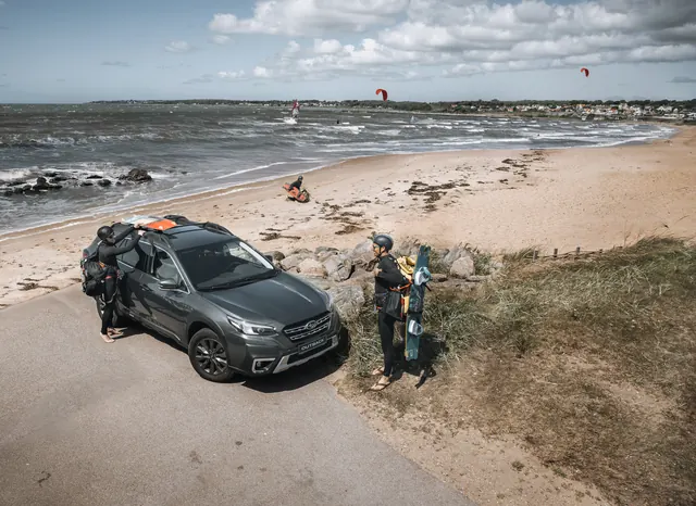 Grå Subaru Outback vid en sandstrand med havet i bakgrunden